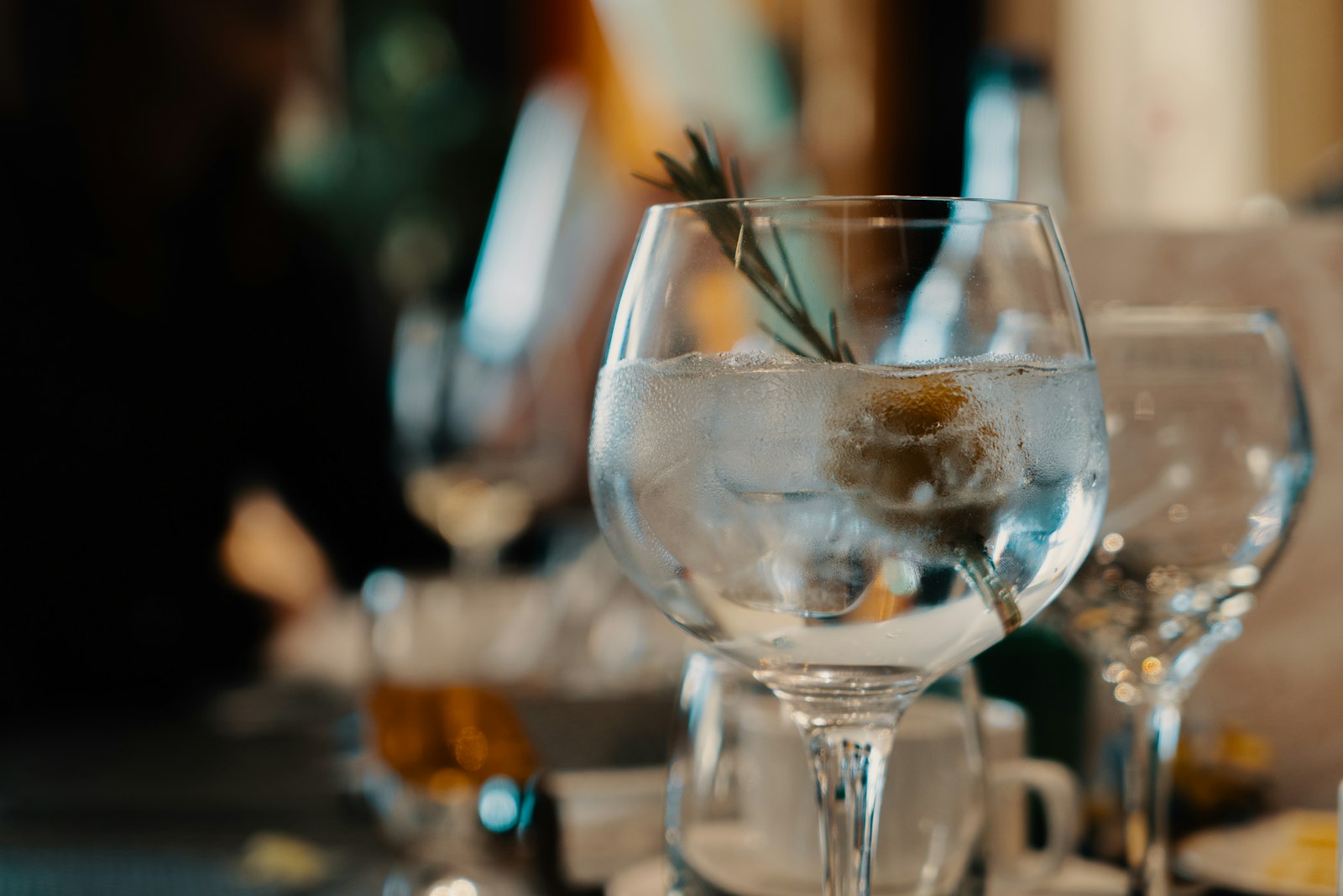 A warm gin cocktail in a stemmed glass beside juniper, apple and cinnamon