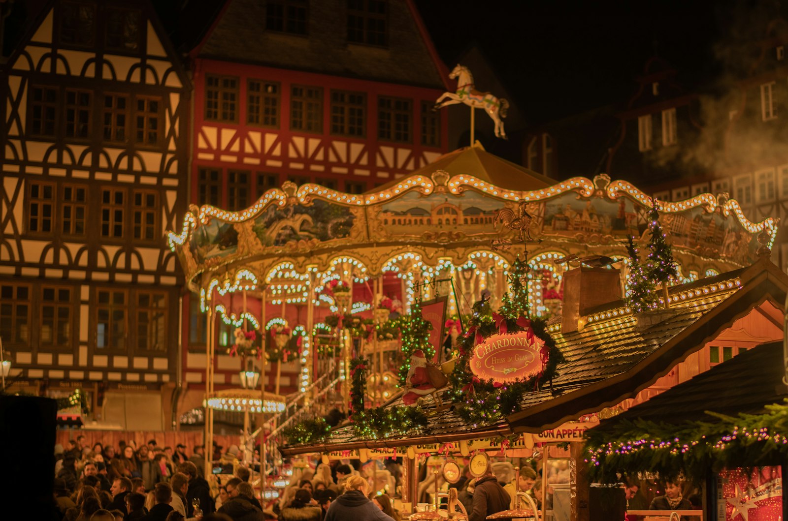 A wooden Christmas market stall serving steaming red Glühwein in decorated mugs under festive lights.