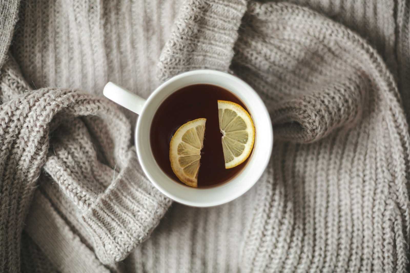 A steaming glass of hot toddy with a lemon wheel and cinnamon stick.
