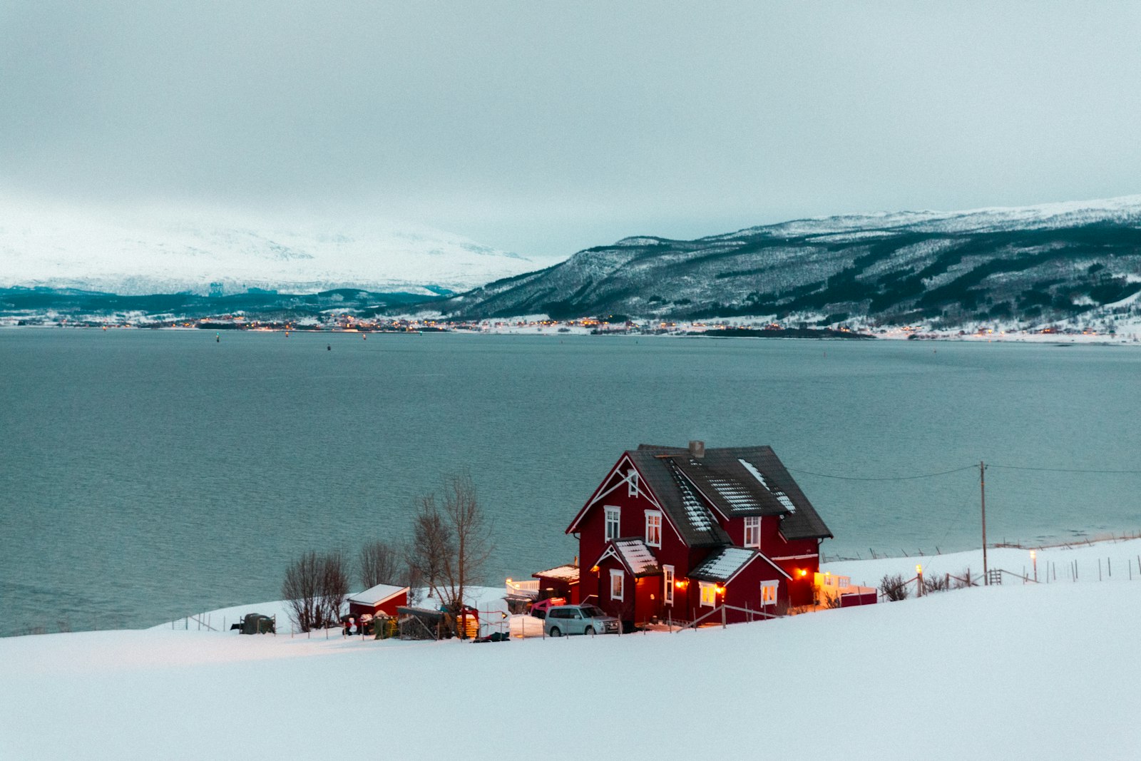 A steaming glass of red glögg with raisins and almonds beside candles in a dim Nordic interior.