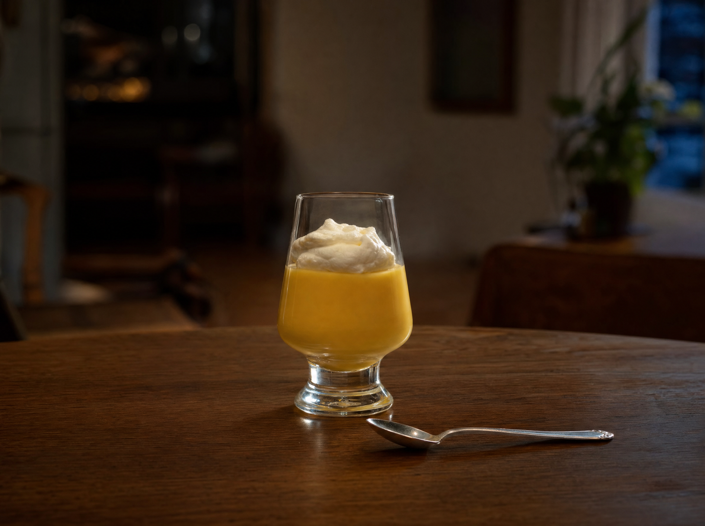 A small glass of thick golden advocaat dusted with cocoa powder.