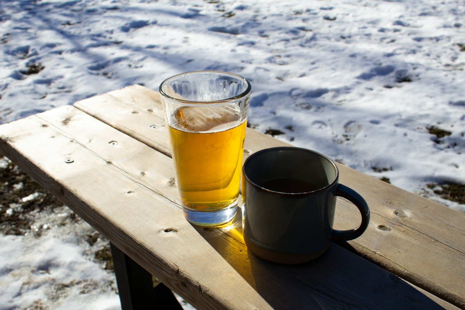 A large pan and heatproof mugs of British wassail with roasted apples floating among cinnamon and ginger.