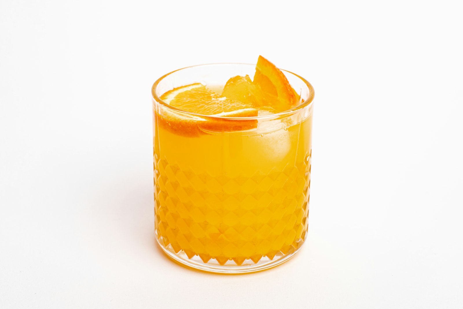 A Christmas Old Fashioned in a rocks glass with orange peel and cinnamon stick