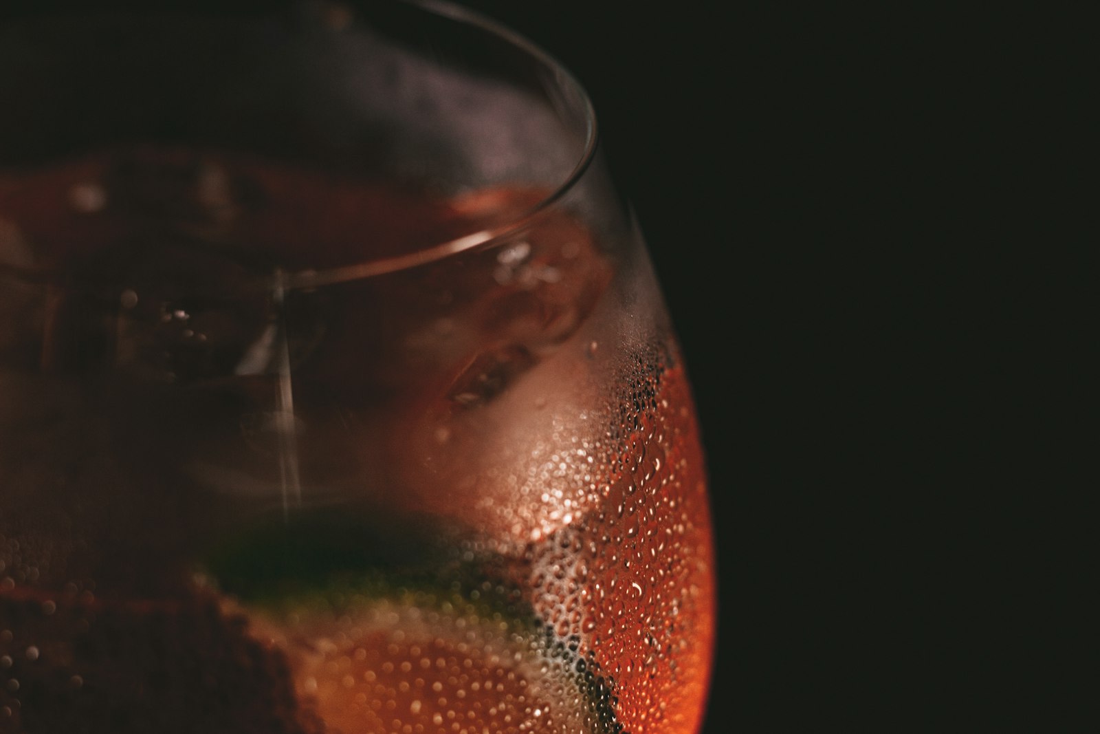 A Christmas Spritz in a wine glass with cranberries, rosemary and orange peel