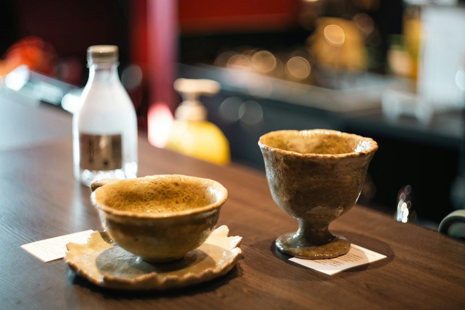 Small heatproof cups of warm spiced sake with ginger slices and a star anise.