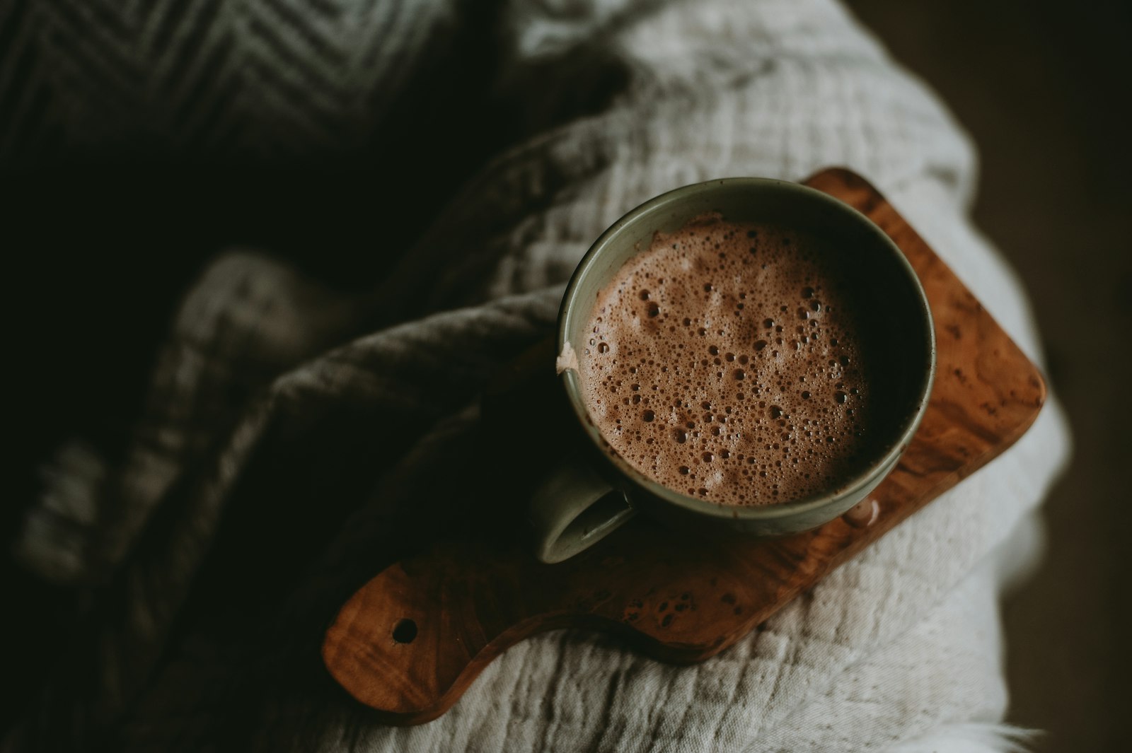 A heatproof mug of spiced coconut hot chocolate topped with toasted coconut flakes.