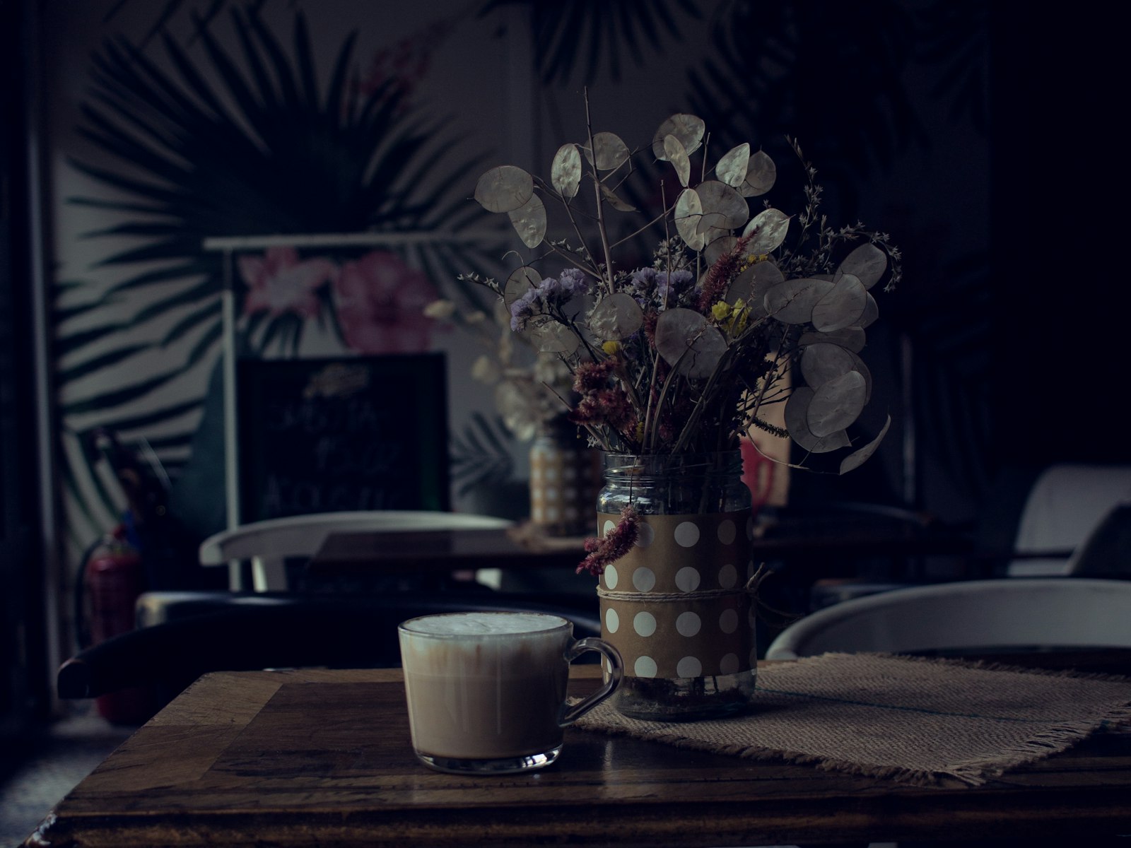 A heatproof mug of spiced oat milk latte topped with foam and a dusting of cinnamon.