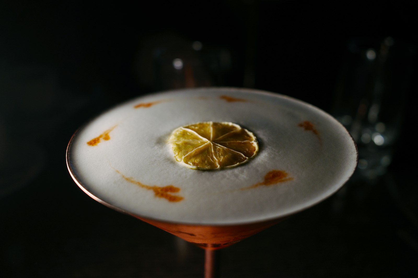 Spiced Pisco Sour in a coupe with Angostura bitters dotted across white foam