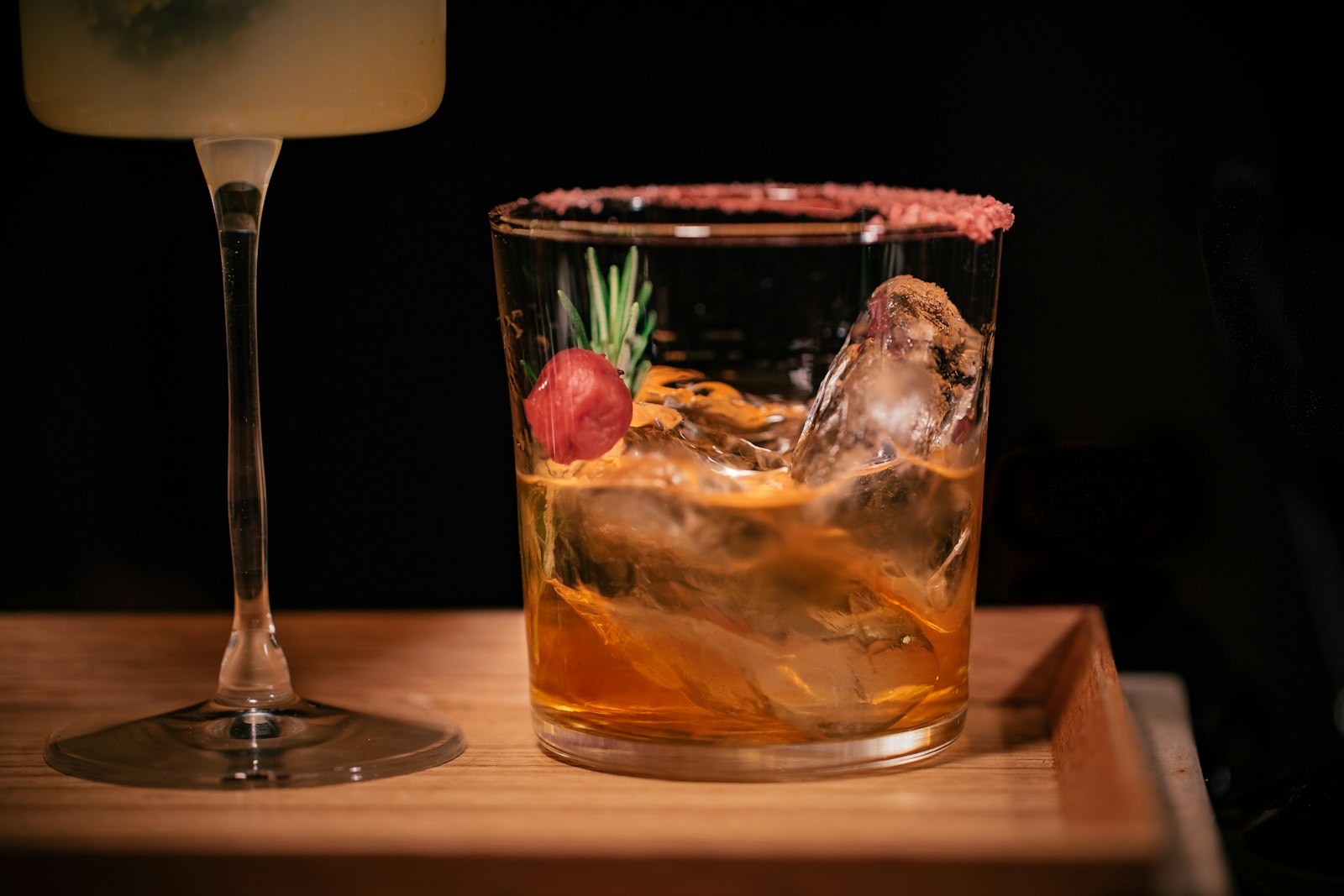 Star anise rum sour in a coupe glass with a thin lime wheel and whole star anise pod resting on top, warm amber colour.