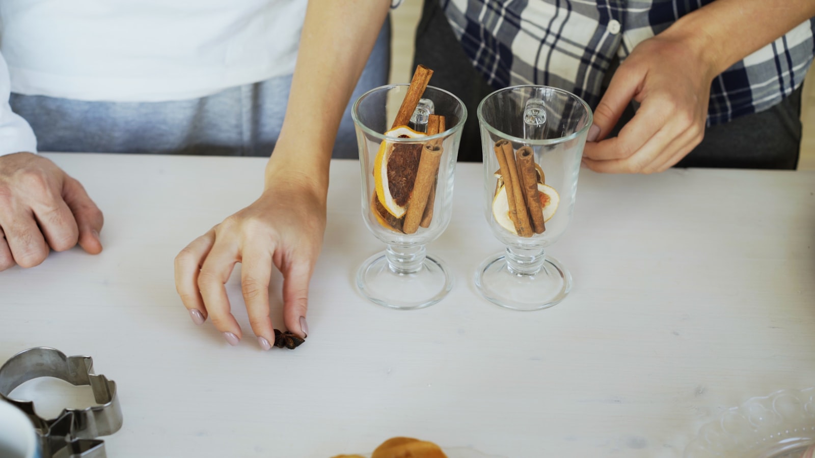 A glass of deep-red French vin chaud garnished with an orange slice and cinnamon stick.