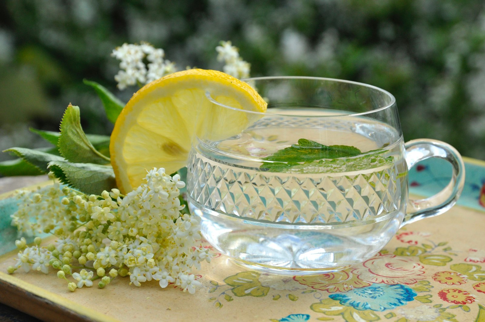 A warm elderflower gin cocktail in a heatproof mug with a lemon twist.