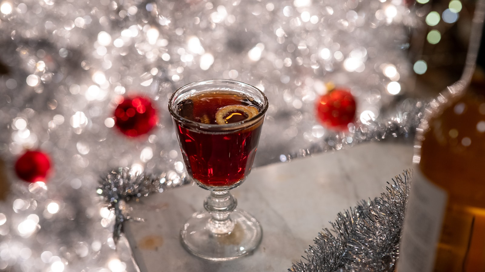 A heatproof glass of warm ruby port and lemon with a cinnamon stick and a slice of lemon.