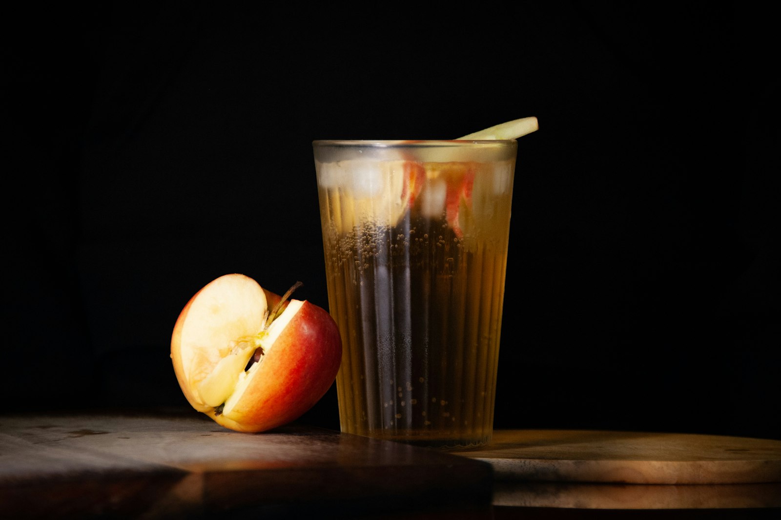 A heatproof glass of warm spiced apple juice with orange slices, a cinnamon stick and star anise.
