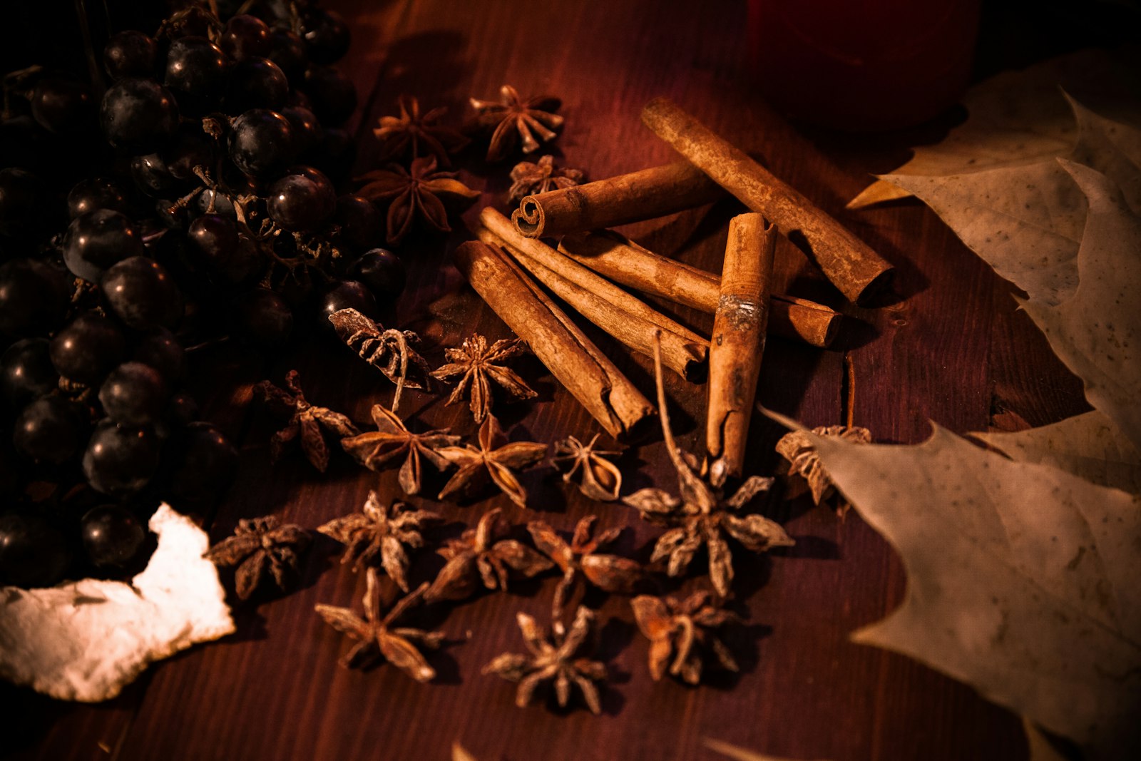 A heatproof glass of golden wassail with baked apple and a cinnamon stick.