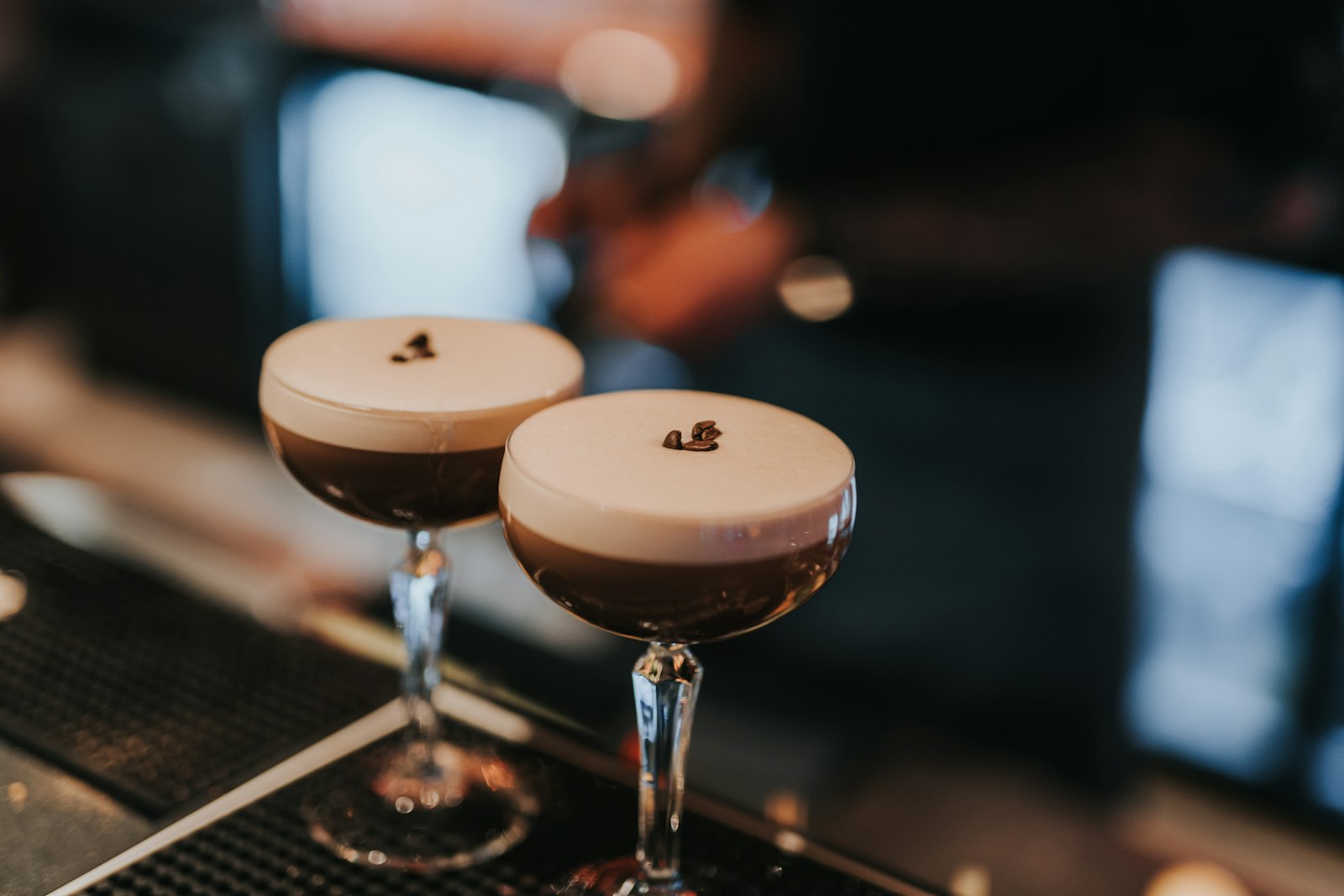 A winter espresso martini in a stemmed glass topped with a smooth crema and three coffee beans.